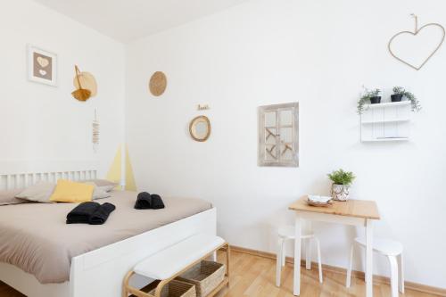 a white bedroom with a bed and a table at XX SETTEMBRE 69 in Trieste