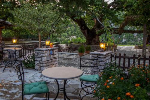 a patio with a table and chairs under a tree at En Chora Vezitsa in Vitsa