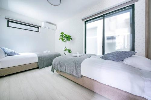 a bedroom with two beds and a large window at ぷふか東向島3 in Tokyo