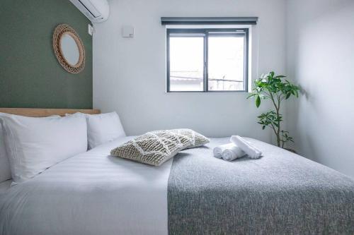 a bedroom with a large white bed with a window at ぷふか東向島3 in Tokyo