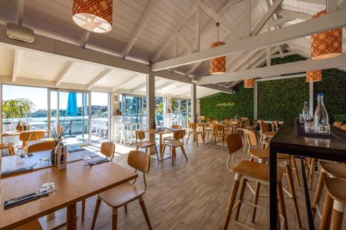 a restaurant with wooden tables and chairs and windows at Palm Beach Cottage with Private Spa Pool in Palm Beach