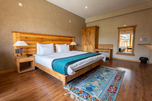 Schlafzimmer mit einem großen Bett mit einem Kopfteil aus Holz in der Unterkunft The Saraha in Leh
