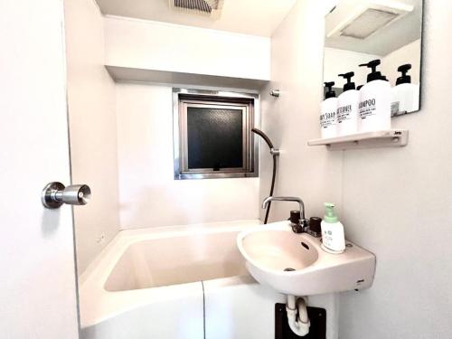 a white bathroom with a sink and a bath tub at Ikebukuro Sugamo 駅近 C02 in Tokyo