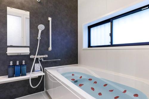 a bathroom with a bath tub and a window at LOA Chatan Resort in Chatan