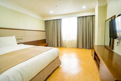 a hotel room with a bed and a flat screen tv at Jeju Robero in Jeju