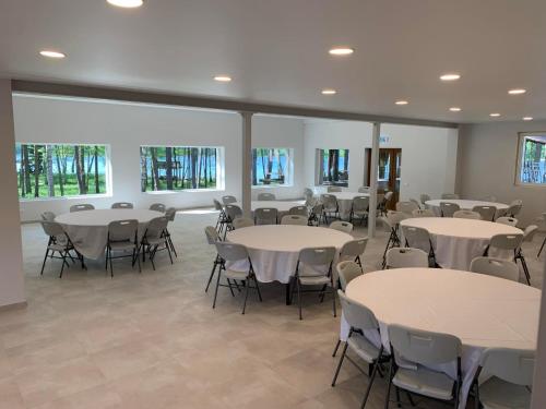 a room with white tables and chairs and windows at Sodyba Ažvintis in Švedriškė