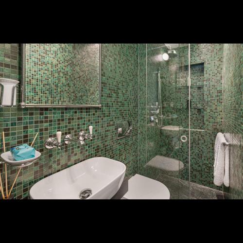 een groene betegelde badkamer met een toilet en een glazen douche bij Luxury Suite in Cadogan Square II in Londen