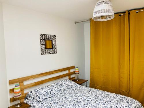 a bedroom with a bed and a yellow curtain at Joli F2 avec terrasse 150m plage in Saint-Aubin-sur-Mer