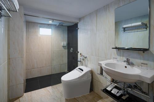 a bathroom with a sink and a toilet and a mirror at Swiss-Belhotel Makassar in Makassar