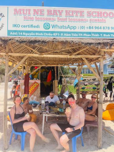 a group of people sitting at a table on the beach at Mui Ne Garden Hotel and Kite School in Mui Ne