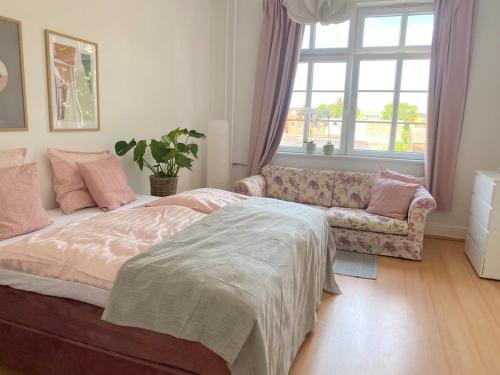 a bedroom with a bed and a couch and a window at Boutique lejlighed Nakskov in Nakskov