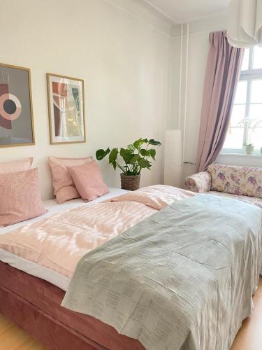 a bedroom with a bed with pink pillows and a plant at Boutique lejlighed Nakskov in Nakskov