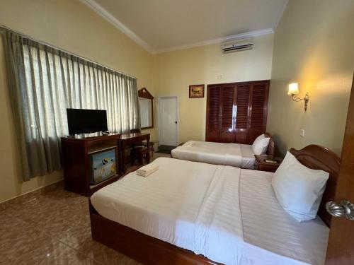 a hotel room with two beds and a television at Samrongsen Hotel in Kampong Chhnang