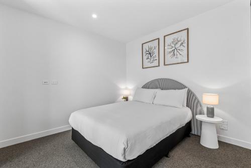 biała sypialnia z łóżkiem i stołem w obiekcie Elegant 1-Bed by Shops with Rooftop Swimming Pool w Melbourne