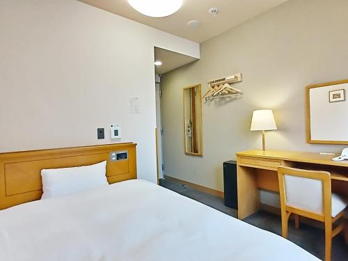 青森市にあるホテルルートイン青森中央インターのベッド、デスク、デスクが備わる客室です。