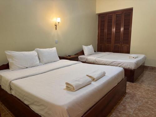Dos camas en una habitación de hotel con toallas. en Samrongsen Hotel, en Kampong Chhnang