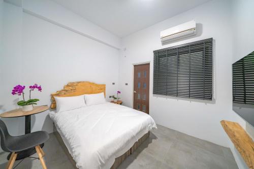 a bedroom with a bed and a table and a chair at Tianshe Xiangsui B&B in Hualien City