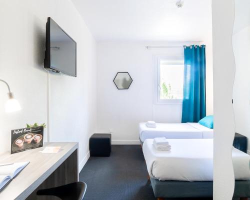 Cette chambre comprend deux lits, un bureau et une télévision. dans l'établissement Hôtel Lapeyronie, à Montpellier