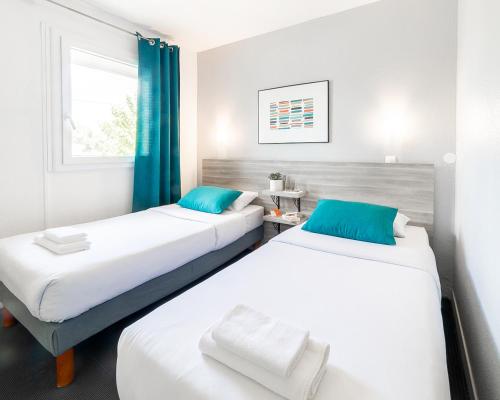 - 2 lits dans une chambre dotée de rideaux bleus dans l'établissement Hôtel Lapeyronie, à Montpellier