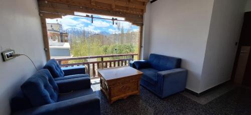 a living room with two blue chairs and a window at Greater Ladakh Residency in Leh