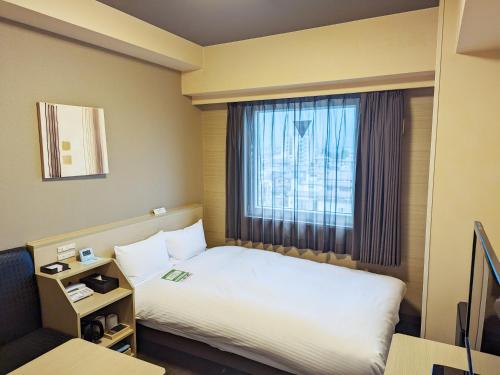 Hotel Route-Inn Oshu في Oshu: غرفه فندقيه بسرير ونافذه