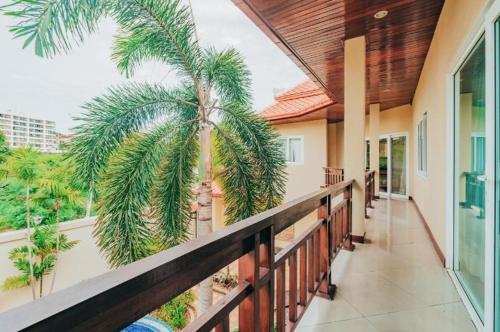 a balcony of a house with a palm tree at Luxury Garden Pool Villa near Beach & Walking Street in Pattaya South