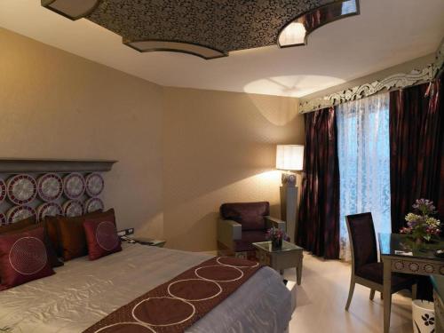 a bedroom with a bed and a table and a chair at Hotel Grand regus in Bangalore