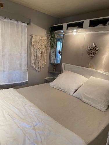 une chambre avec un grand lit blanc avec une fenêtre dans l'établissement Camping Oasis village, à Puget-sur Argens