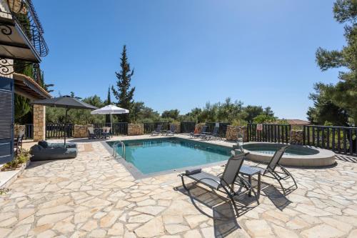 a swimming pool with two chairs and an umbrella at Aresti Mountain Resort in Agios Leon
