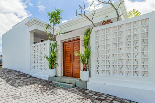 uma casa branca com uma porta de madeira e vasos de plantas em Belvilla 93868 Hii Inn em Uluwatu