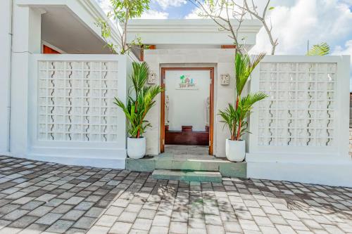 a white house with two potted plants in front of a door at Belvilla 93868 Hii Inn in Uluwatu