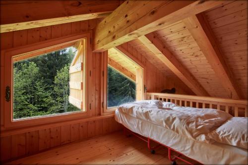 una camera da letto in una baita di tronchi con una grande finestra di Lioda Wood a Cibiana