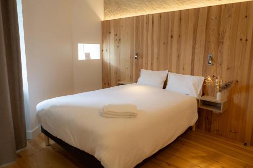 une chambre avec un grand lit blanc avec des serviettes dessus dans l'établissement Le Bercail, à Lacaze