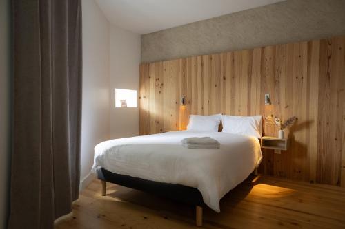 - une chambre avec un grand lit et un mur en bois dans l'établissement Le Bercail, à Lacaze