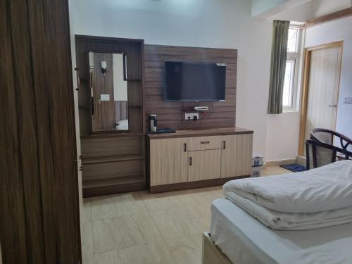 a hotel room with a television and a bed at Hill side hotel in Karnaprayāg