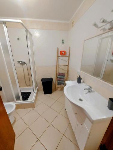 a white bathroom with a shower and a sink at Casa Vaso in Moncarapacho