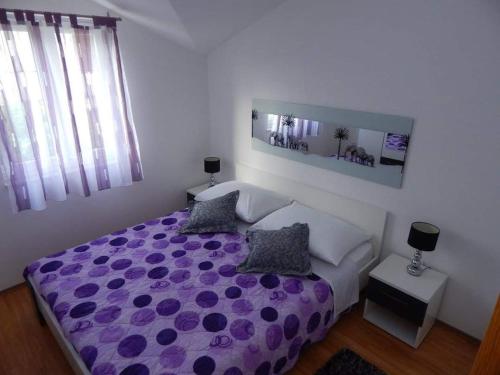 1 dormitorio con 1 cama morada y 2 almohadas en Apartmani Mastrinka, en Vinišće