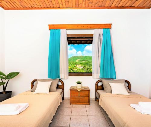 two beds in a room with a window at Sivota Royal in Syvota