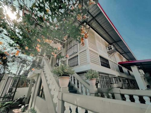 a white house with potted plants on a railing at 1898 Casa and Restaurante in Silay