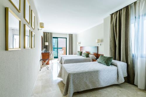 トレ・デル・マールにあるHotel Torremar - Maresのベッド2台とソファが備わるホテルルームです。
