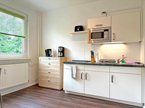 cocina con armarios blancos y microondas en Hammerhotel Apartments Halle Saale, en Halle an der Saale