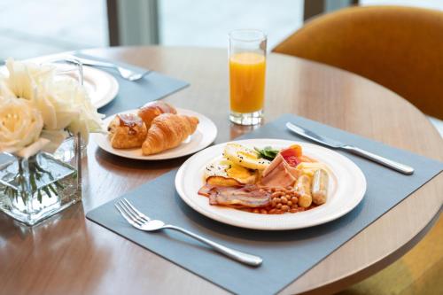 a table with two plates of food and a glass of orange juice at Fraser Place Wujiaochang Shanghai - Adjoin business center, free minibar in Shanghai