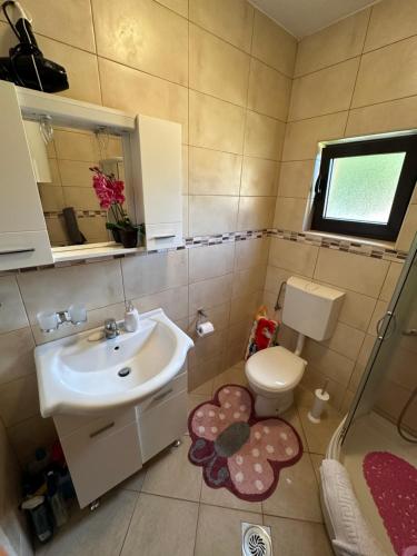 un bagno con lavandino, WC e finestra di Stojovic house a Žabljak