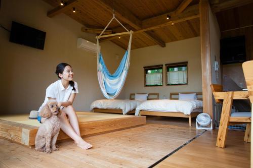 Une fille assise sur un lit avec un chien dans l'établissement THE FARM Resort Japan, à Katori