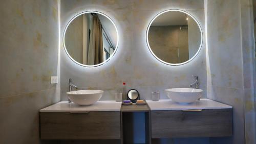 deux lavabos dans une salle de bain avec deux miroirs dans l'établissement Villa Seabel - le standing avec piscine et vue mer, à Hyères