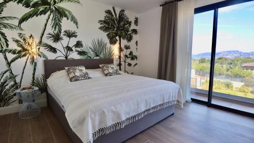 une chambre avec un lit et une grande fenêtre dans l'établissement Villa Seabel - le standing avec piscine et vue mer, à Hyères