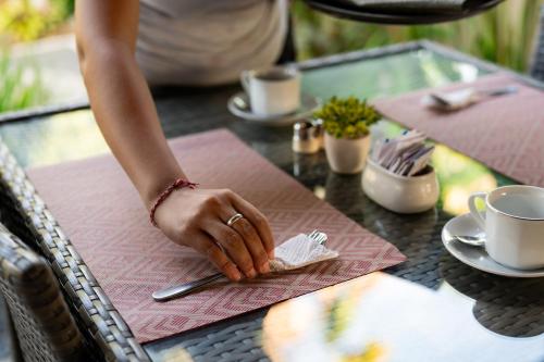 a person is sitting at a table with a fork and napkin at D'Puncak Villas Lembongan in Nusa Lembongan