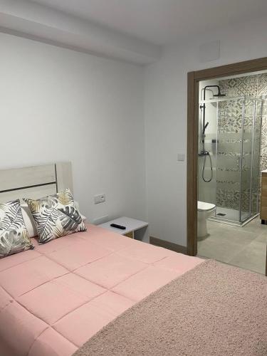 a bedroom with a pink bed and a bathroom at Pension Casa Pedro in Fisterra