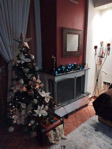 a christmas tree in a living room with a tv at Όμορφο, άνετο ζεστά διακοσμημένο διαμέρισμα in Thérmi