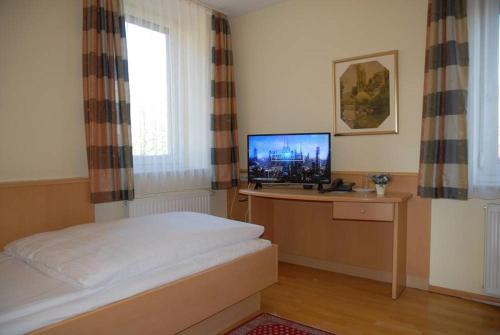 Schlafzimmer mit einem Bett und einem TV auf einem Schreibtisch in der Unterkunft Hotel Garni Grottental in Meßstetten